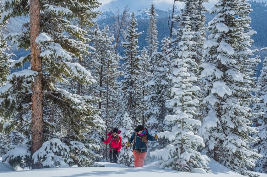 Man and woman hiking in deep snow in snowy forest
