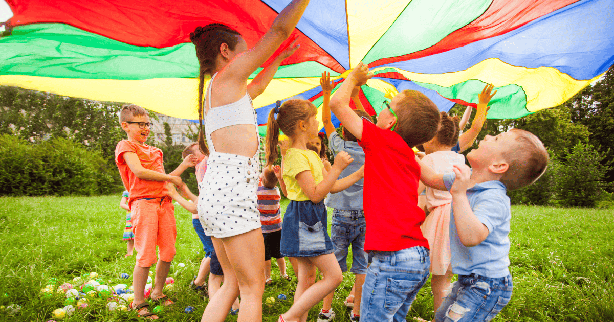Kids playing under a colorful parachute during a fun summer activity in Winter Park.