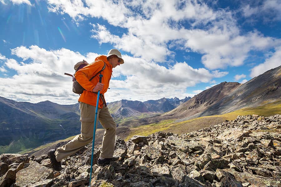 Man hiking with trekking pole in rocky alpine environment