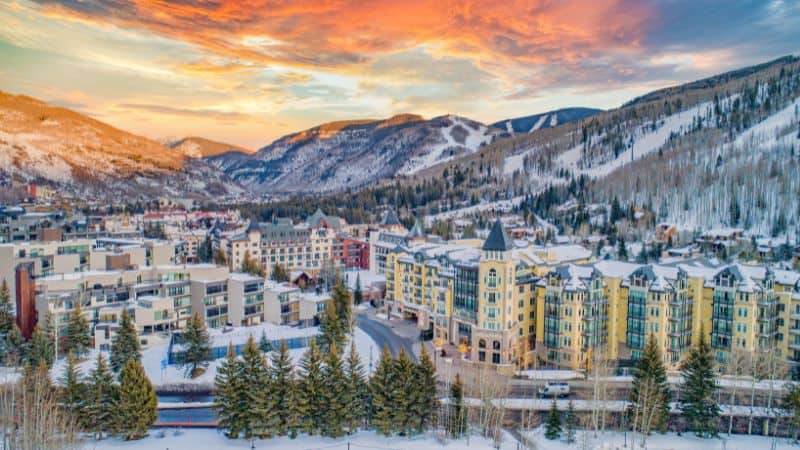 Snow-covered mountain village with colorful buildings at sunset.