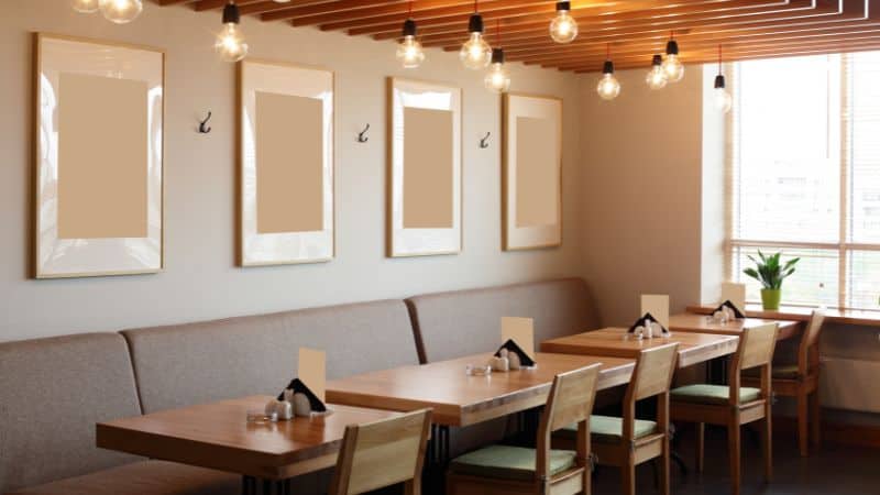 Cozy restaurant interior with wooden tables, bench seating, and hanging lights.