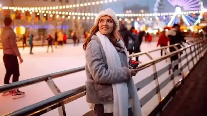 Woman enjoying a drink next to a skating rink