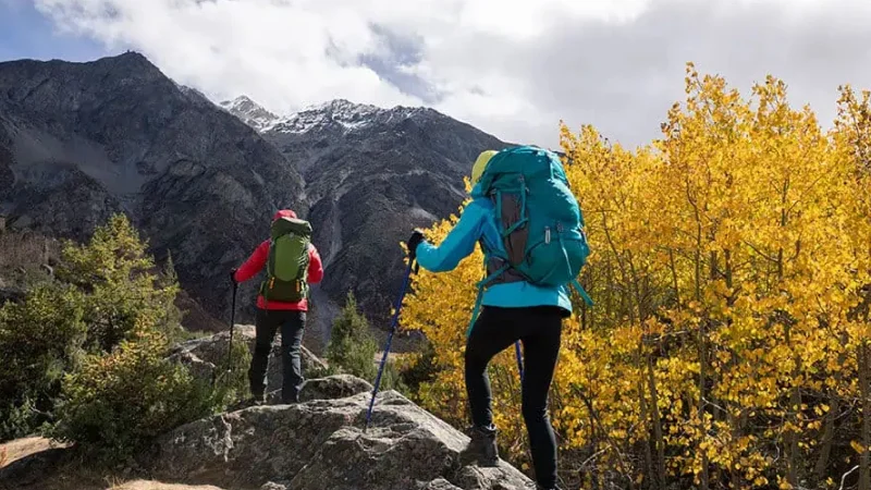Two backpacking hikers on mountain with fall color change
