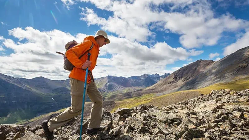 Man hiking with trekking pole in rocky alpine environment